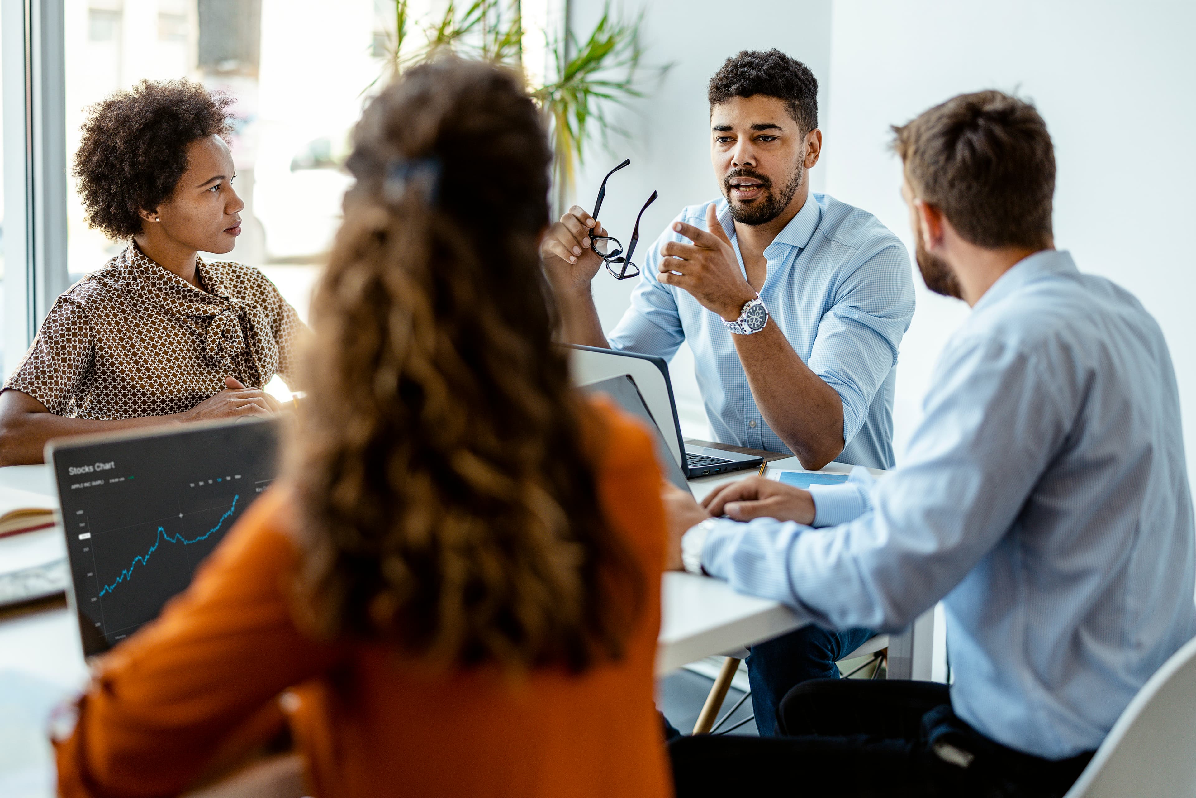 Group of people in suits at an office talking to each other over a conference table